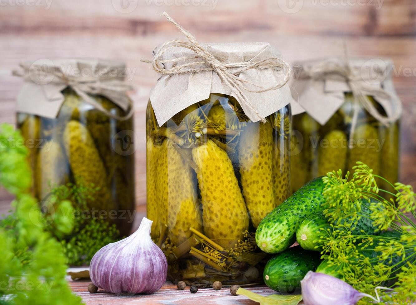 Delicious pickled homemade cucumbers in jars on a wooden background. Close-up. photo