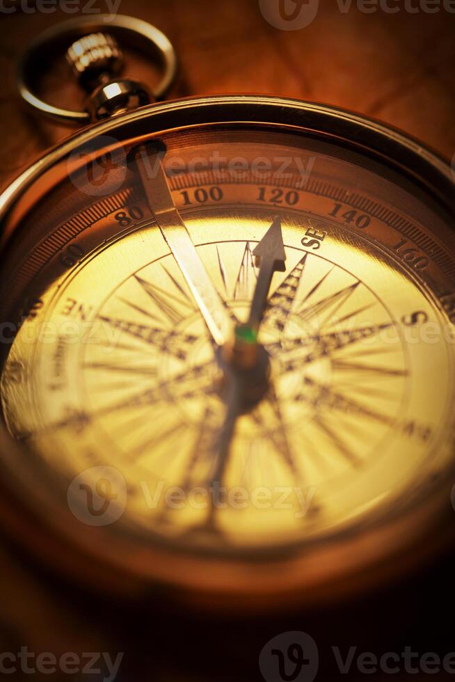 Close-up of an antique compass bathed in a warm glow, showcasing its intricate scale and patina, embodying the spirit of exploration and history. photo