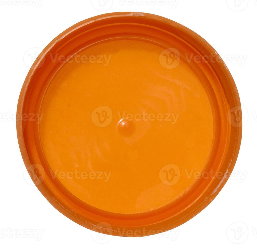 Orange plastic bottle cap on isolated background, top view photo