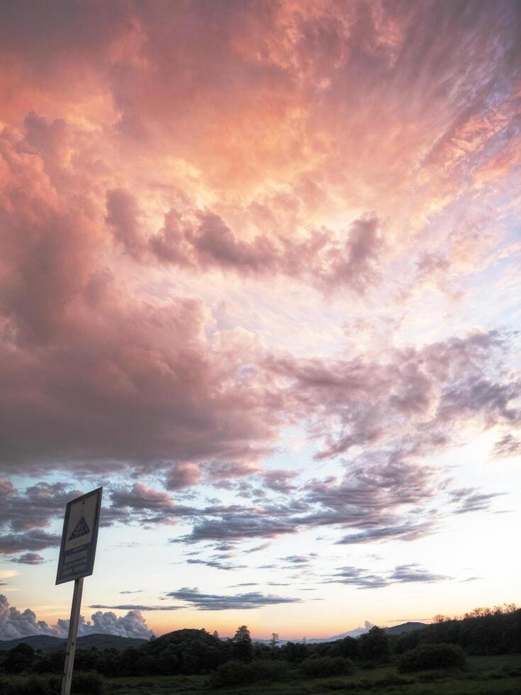 Clouds pink and orange when the sun is setting, traffic sign stops in the lower left corner, beautiful light. photo
