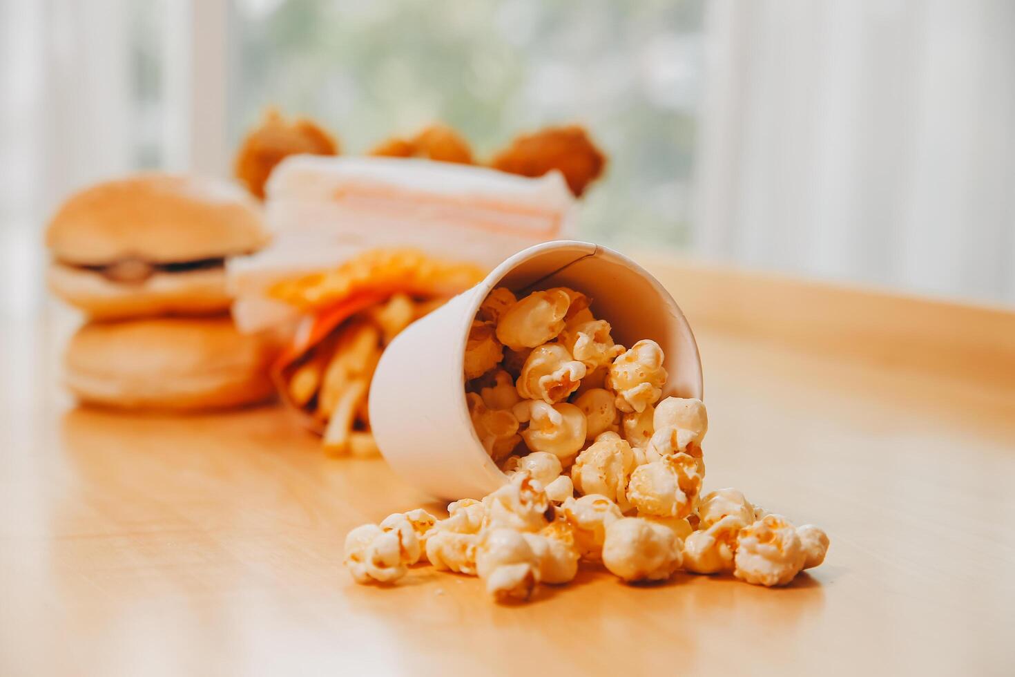 A bucket of popcorn, top-view, warm colors, light brown wooden background, flat lay, daylight macro close-up photo