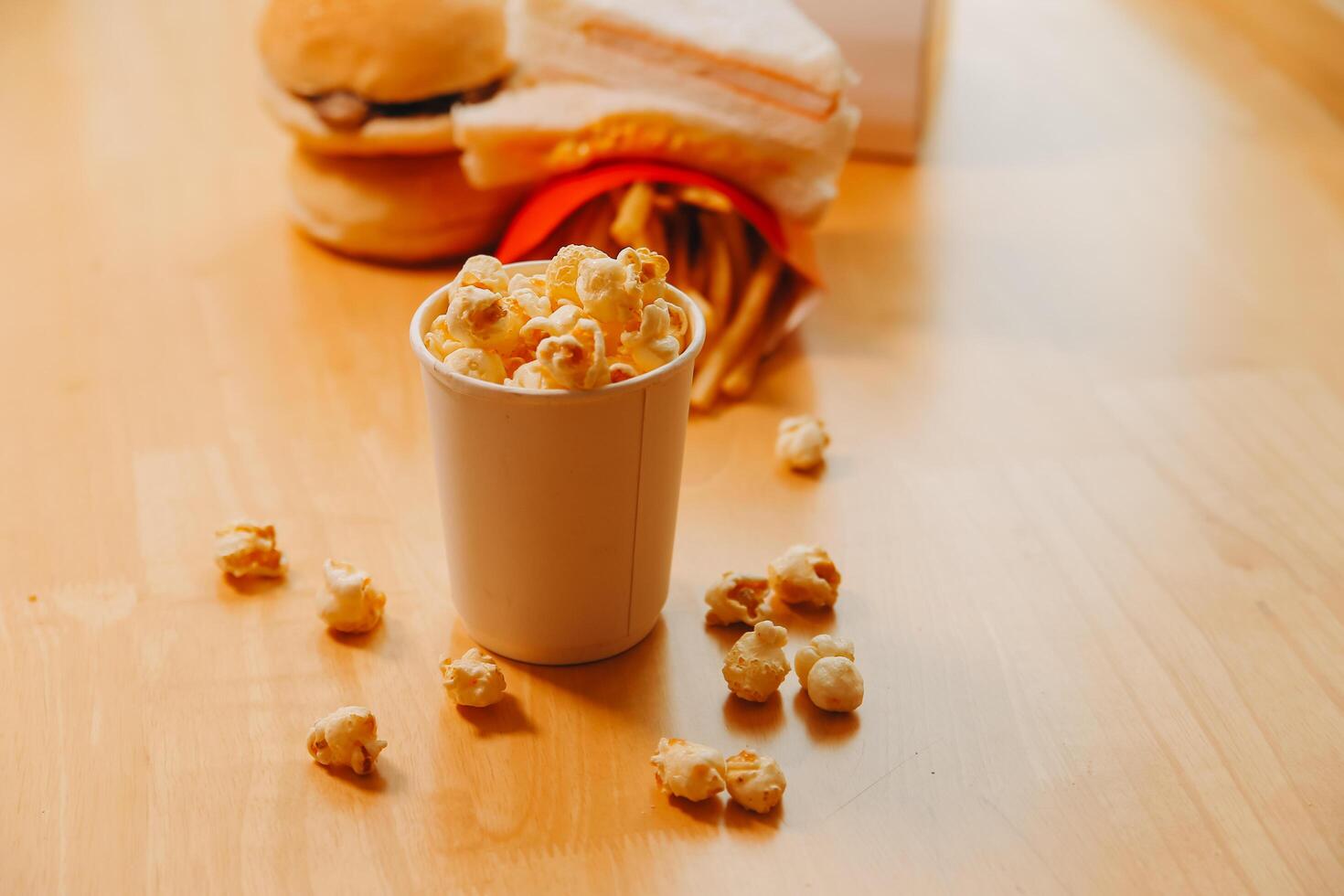 A bucket of popcorn, top-view, warm colors, light brown wooden background, flat lay, daylight macro close-up photo