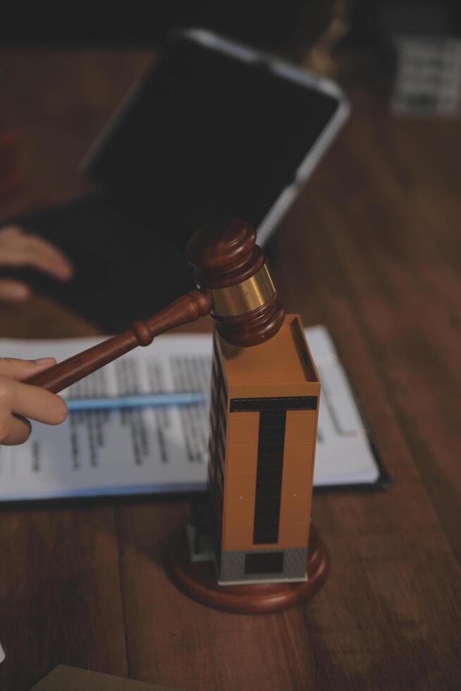 Real Estate Law, Home Insurance, property Tax, Auction and Bidding concepts. small toy house model with gavel justice hammer on desk in courthouse. photo