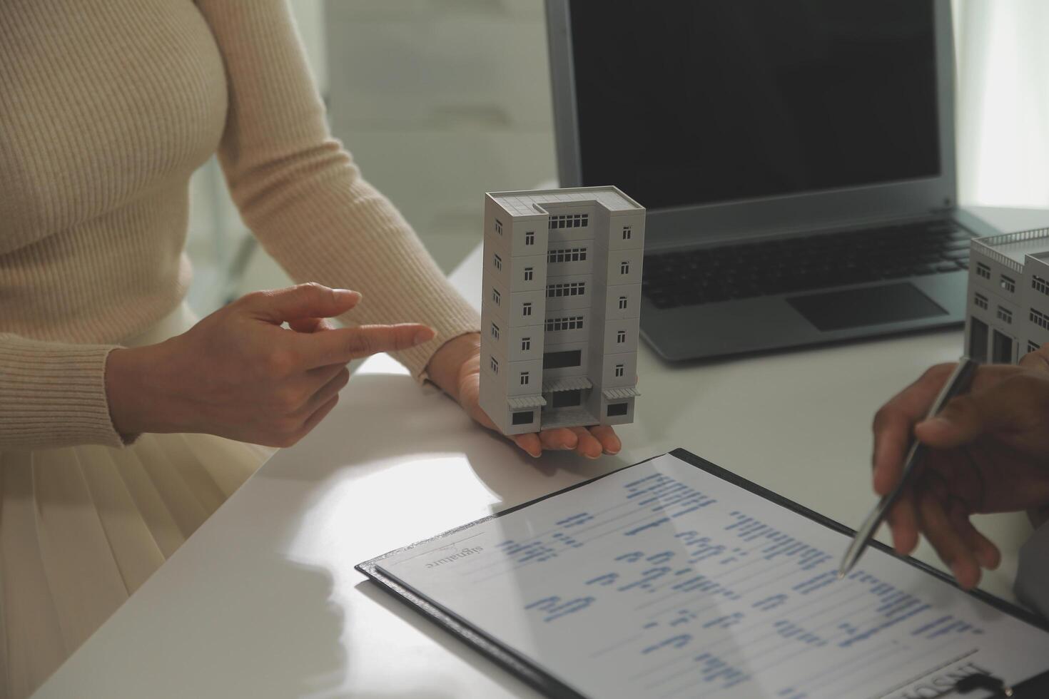 Real estate agent home sales broker is using a pen pointing to the house model and explains the business contract, rent, buy, mortgage, loan, or home insurance photo