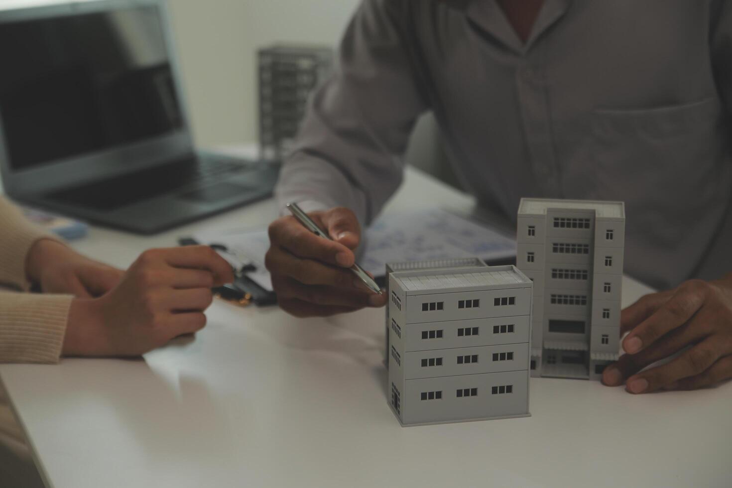 Real estate agent home sales broker is using a pen pointing to the house model and explains the business contract, rent, buy, mortgage, loan, or home insurance photo