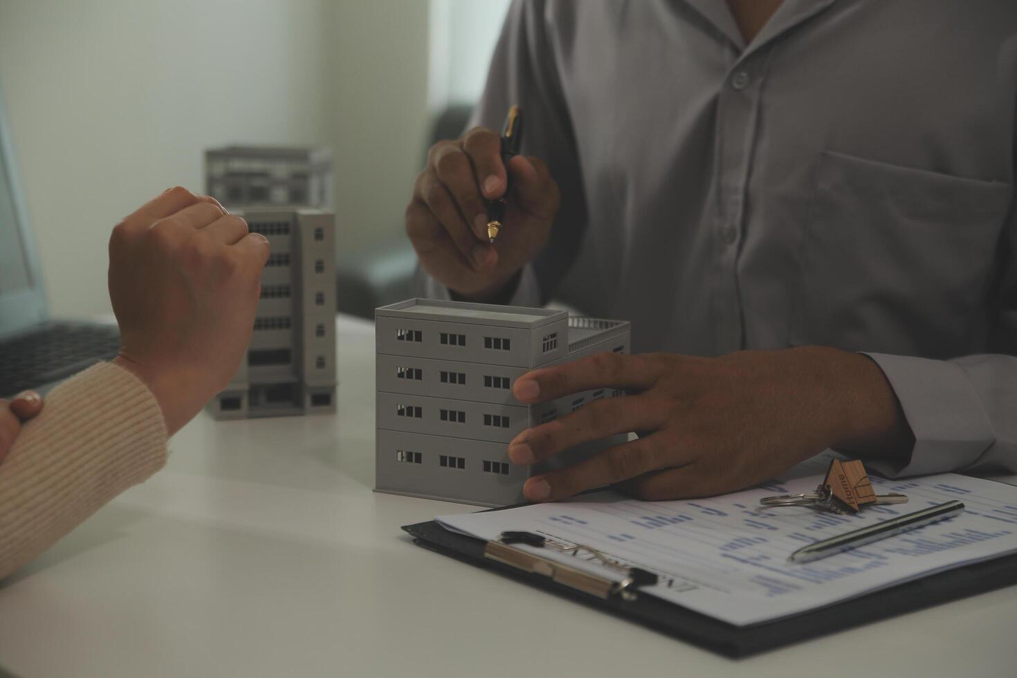 Real estate agent home sales broker is using a pen pointing to the house model and explains the business contract, rent, buy, mortgage, loan, or home insurance photo