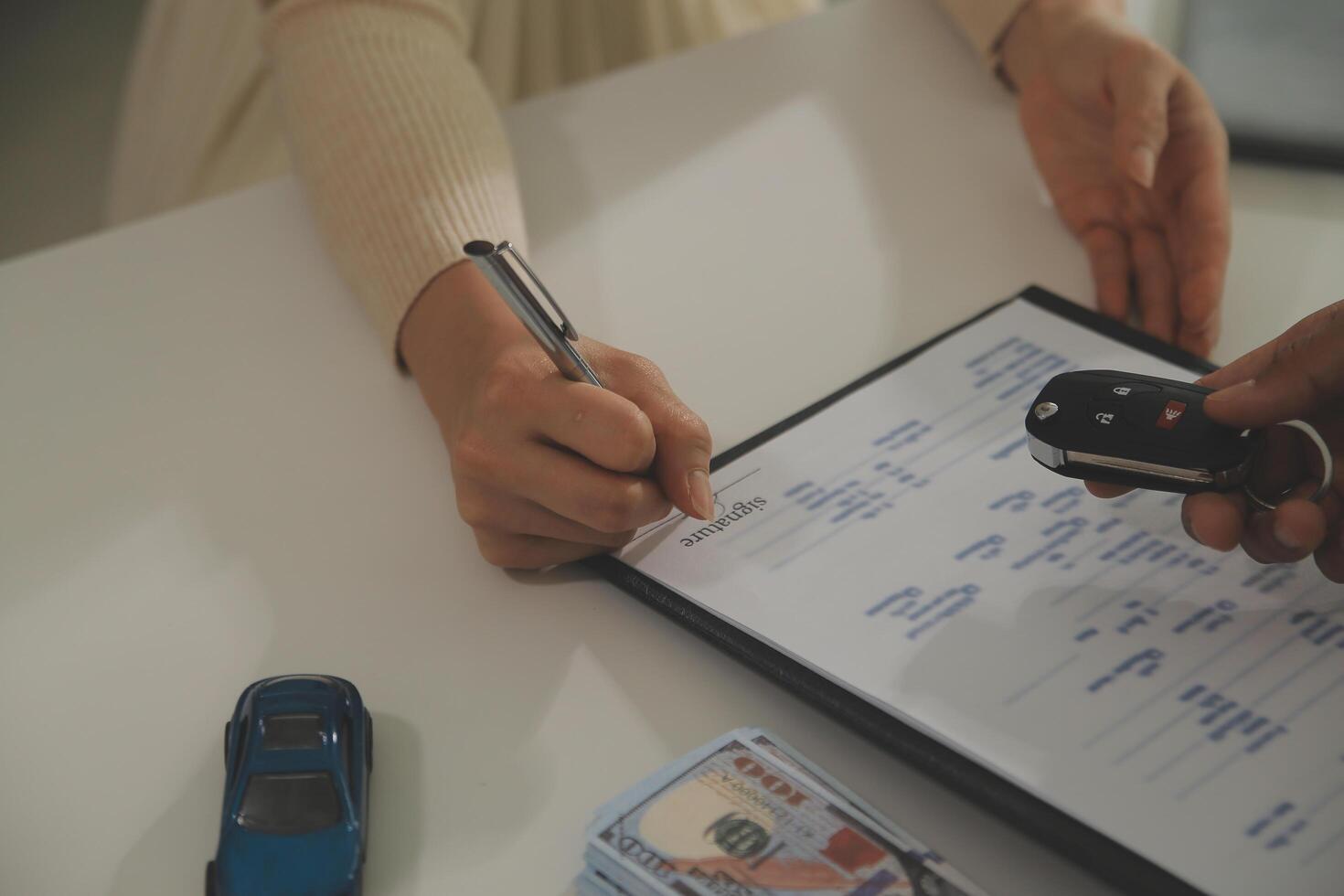 Young man receives a key from car salesman. After agreeing to a contract for rent or sale of a car at workshop, loan car, insurance, sale, buying car and finance concept. photo