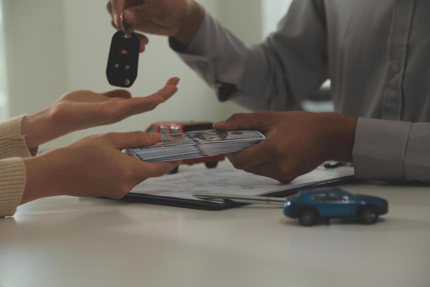 Young man receives a key from car salesman. After agreeing to a contract for rent or sale of a car at workshop, loan car, insurance, sale, buying car and finance concept. photo