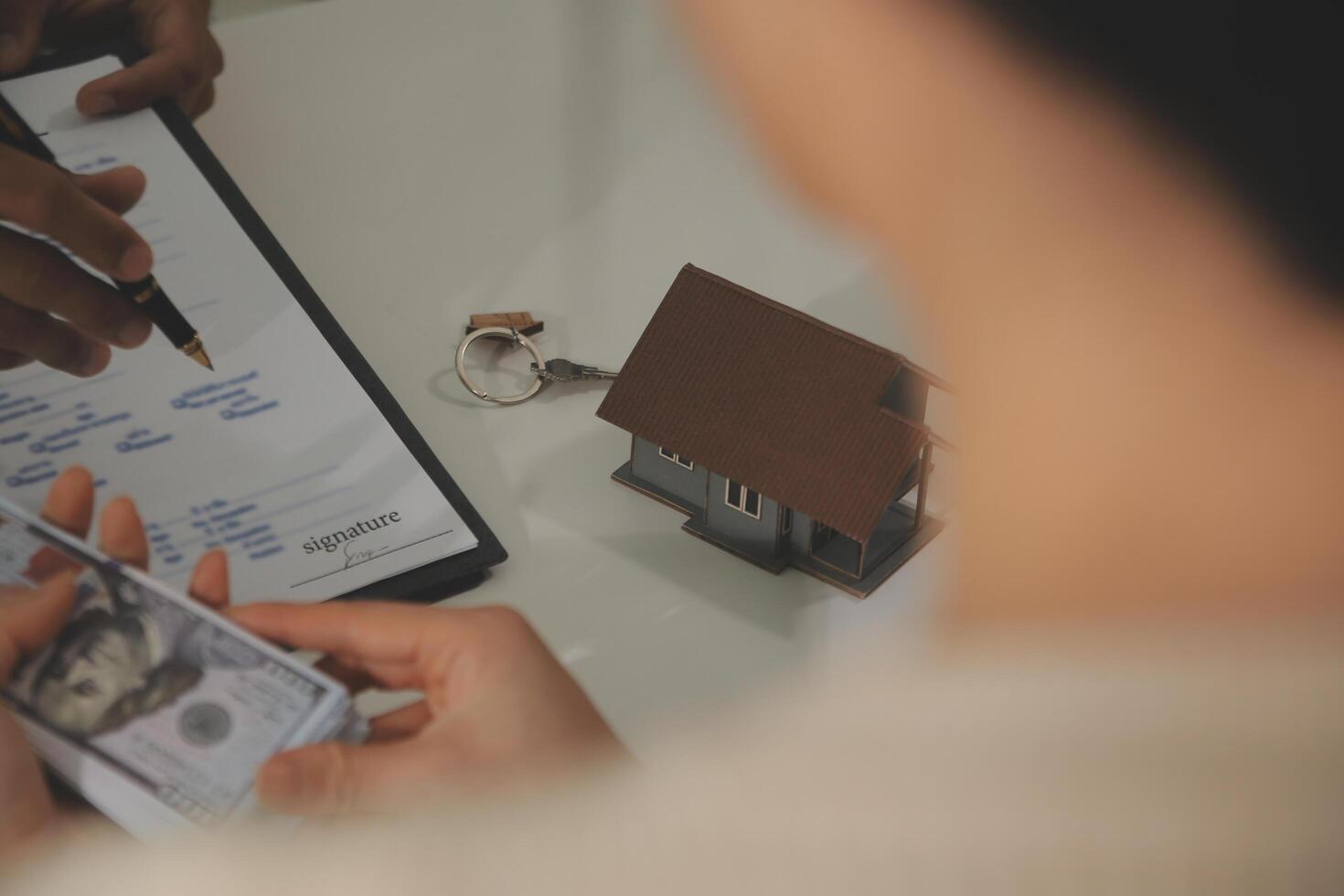 Real estate agent home sales broker is using a pen pointing to the house model and explains the business contract, rent, buy, mortgage, loan, or home insurance photo