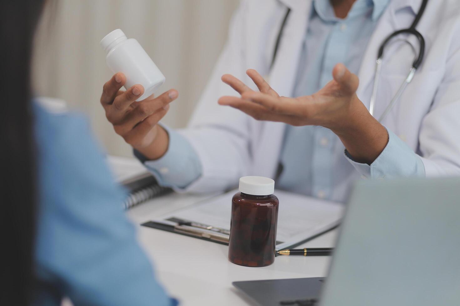 Doctor and patient sitting near each other at the wooden desk in clinic. Female physician's pointing to a records form. Medicine concept photo