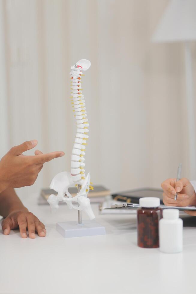 Orthopedists holding digital tablet and pointing at model. Concept of osteoporosis, back pain, lumbar, chiropractic and health. photo