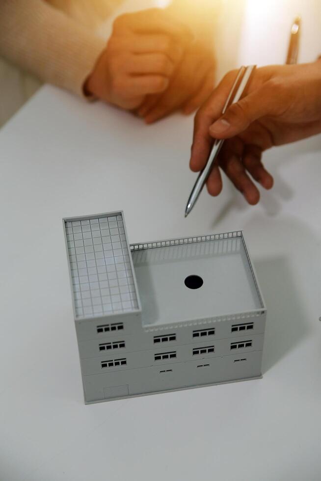 Real estate agent home sales broker is using a pen pointing to the house model and explains the business contract, rent, buy, mortgage, loan, or home insurance photo