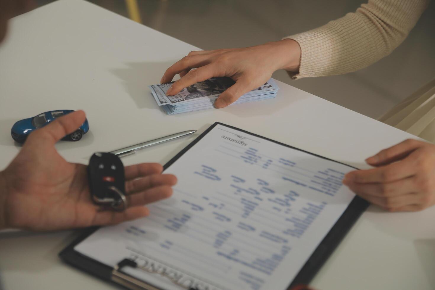 Young man receives a key from car salesman. After agreeing to a contract for rent or sale of a car at workshop, loan car, insurance, sale, buying car and finance concept. photo