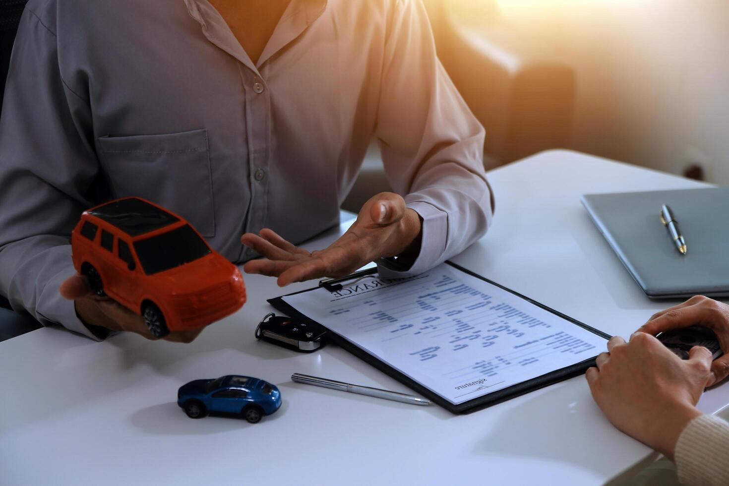 Young man receives a key from car salesman. After agreeing to a contract for rent or sale of a car at workshop, loan car, insurance, sale, buying car and finance concept. photo
