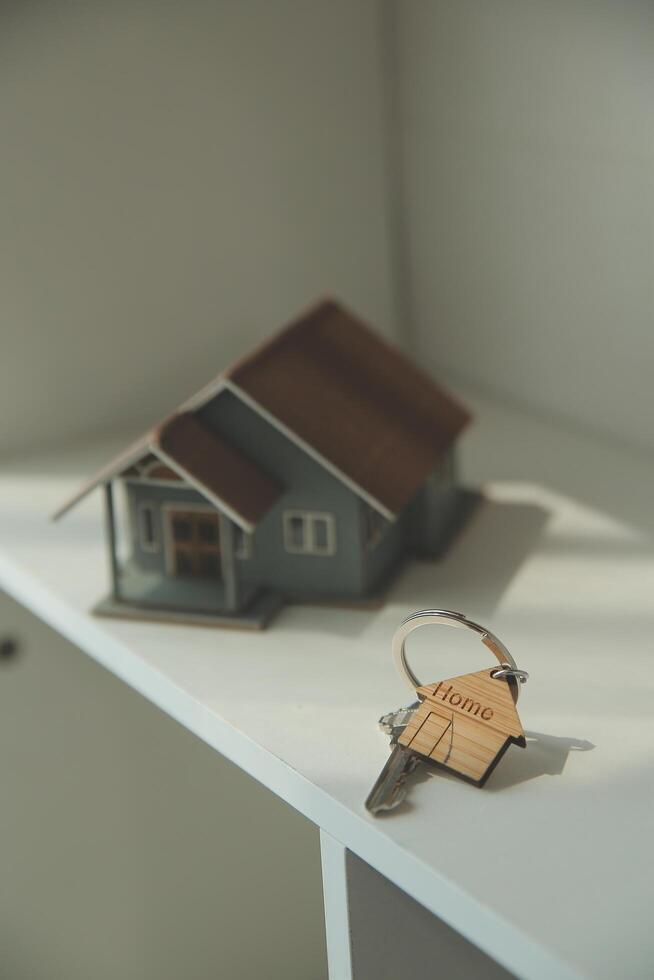 Real estate agent home sales broker is using a pen pointing to the house model and explains the business contract, rent, buy, mortgage, loan, or home insurance photo