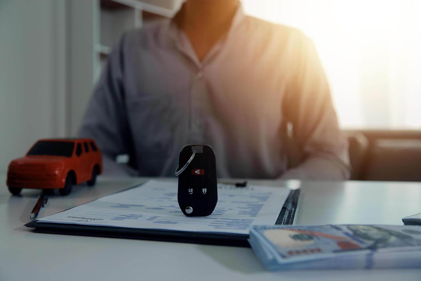Young man receives a key from car salesman. After agreeing to a contract for rent or sale of a car at workshop, loan car, insurance, sale, buying car and finance concept. photo