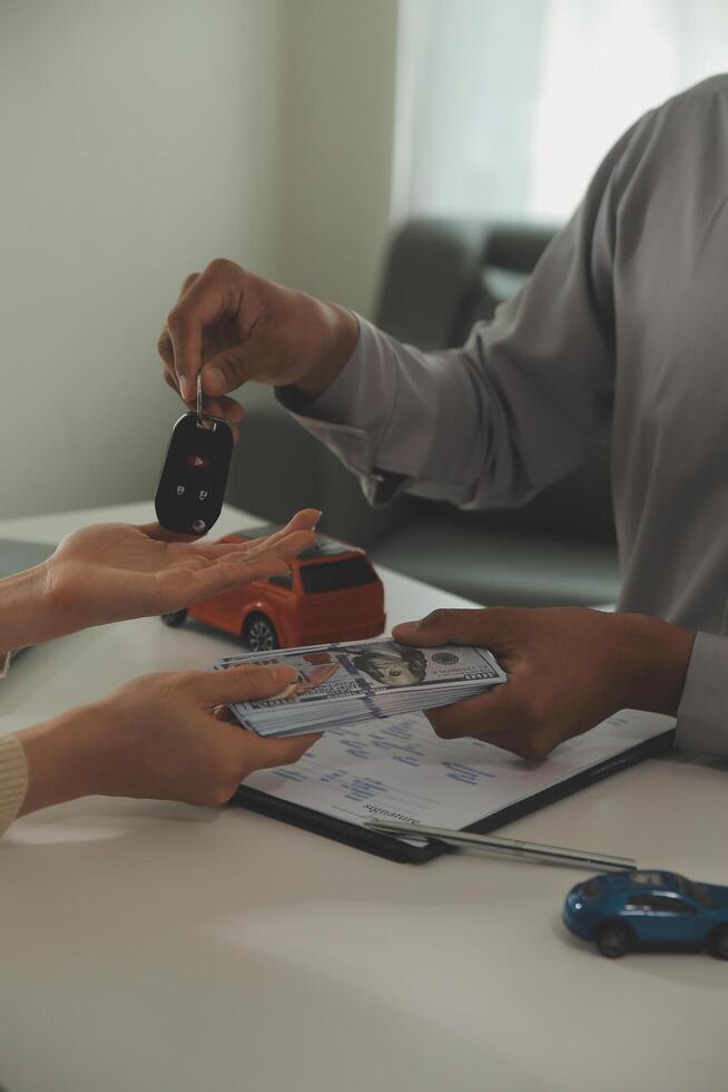 Young man receives a key from car salesman. After agreeing to a contract for rent or sale of a car at workshop, loan car, insurance, sale, buying car and finance concept. photo
