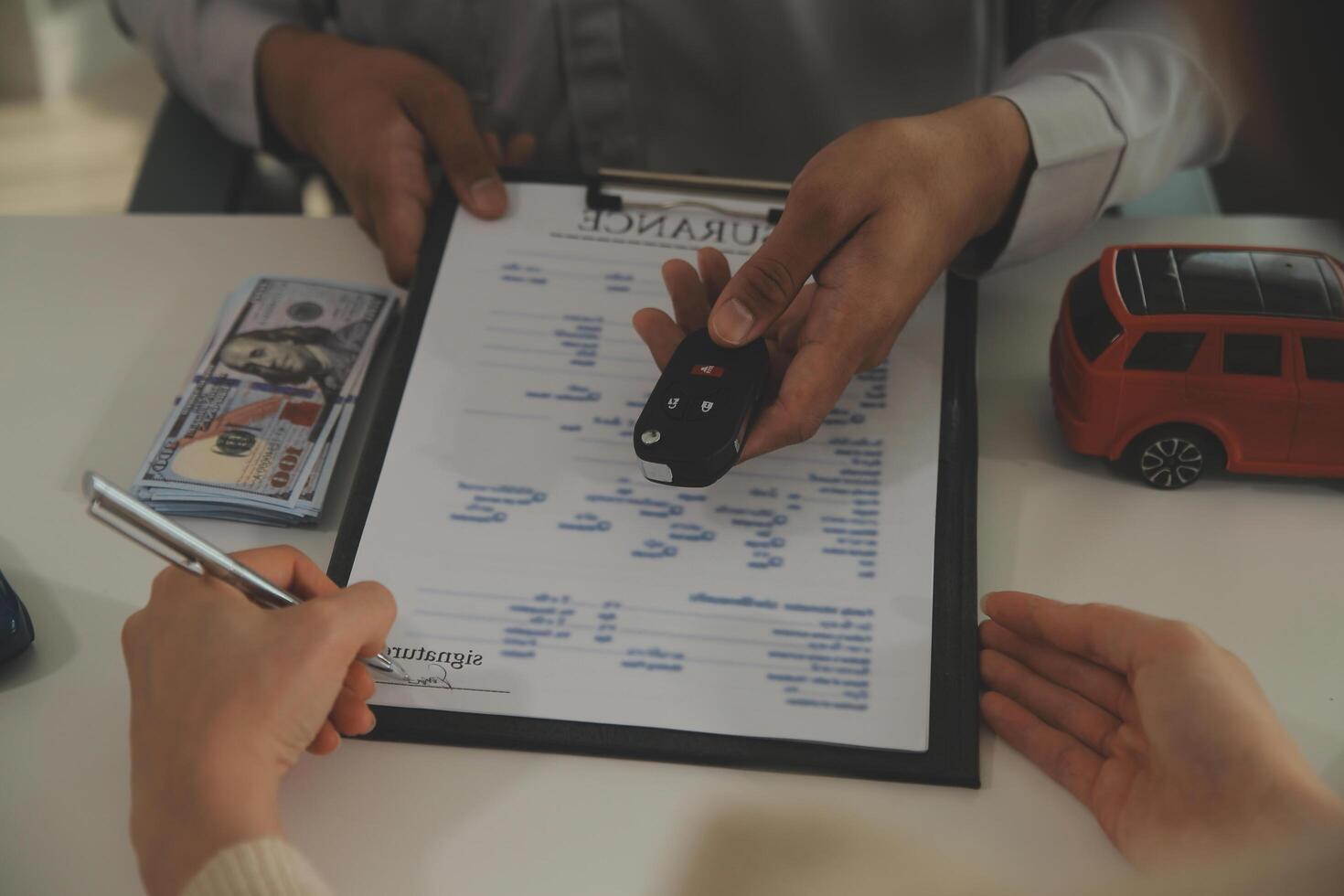 Young man receives a key from car salesman. After agreeing to a contract for rent or sale of a car at workshop, loan car, insurance, sale, buying car and finance concept. photo