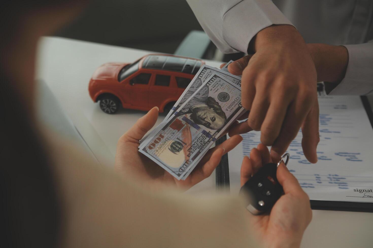Young man receives a key from car salesman. After agreeing to a contract for rent or sale of a car at workshop, loan car, insurance, sale, buying car and finance concept. photo