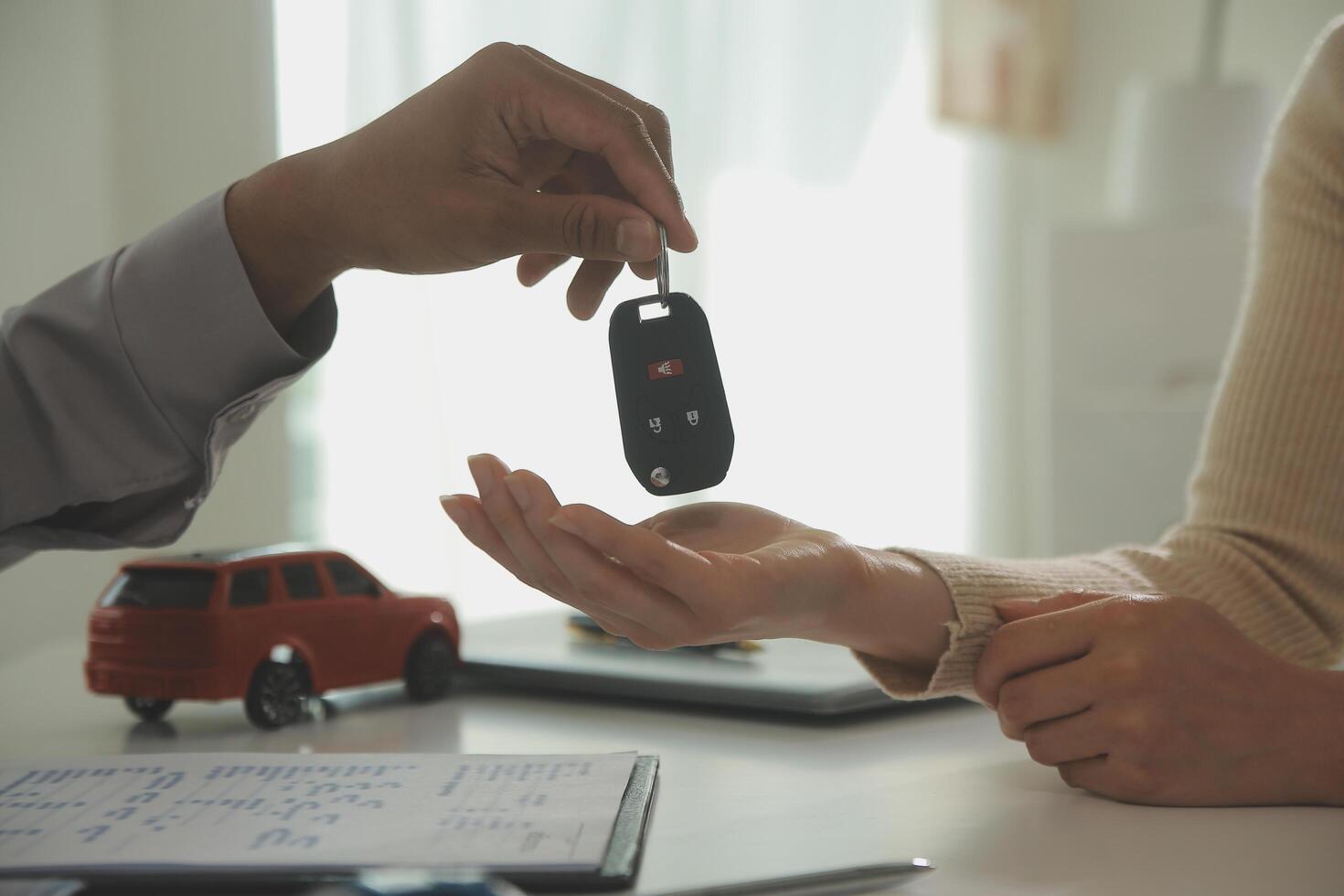 Young man receives a key from car salesman. After agreeing to a contract for rent or sale of a car at workshop, loan car, insurance, sale, buying car and finance concept. photo