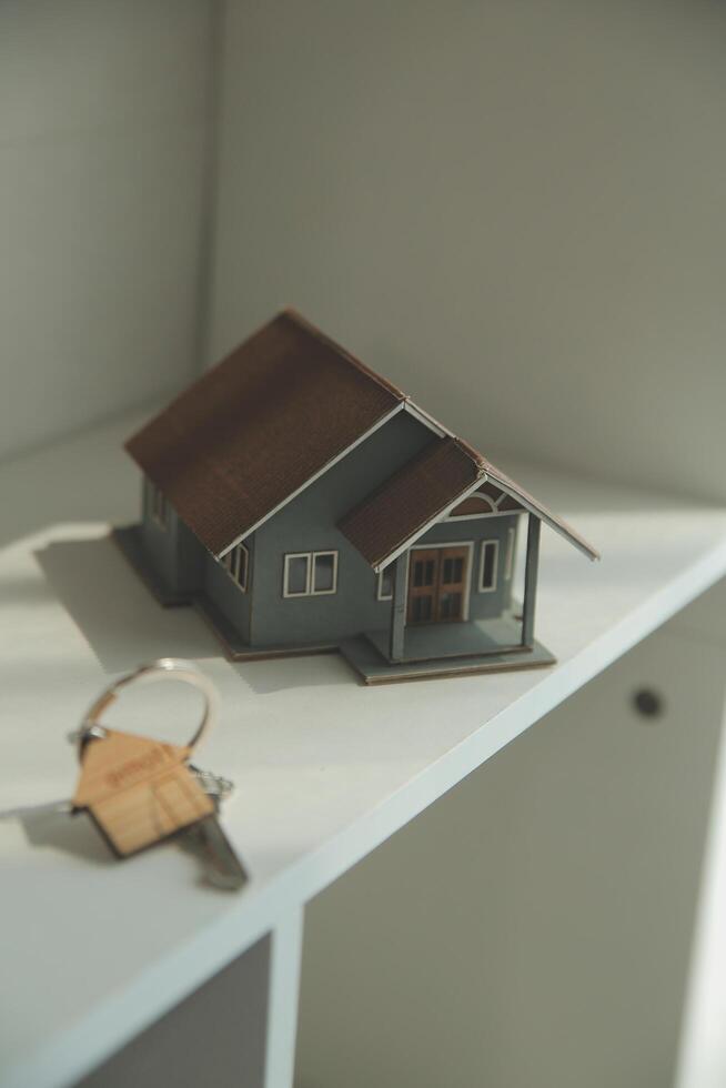 Real estate agent home sales broker is using a pen pointing to the house model and explains the business contract, rent, buy, mortgage, loan, or home insurance photo