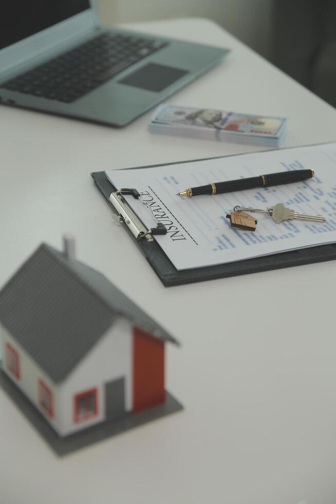 Real estate agent home sales broker is using a pen pointing to the house model and explains the business contract, rent, buy, mortgage, loan, or home insurance photo
