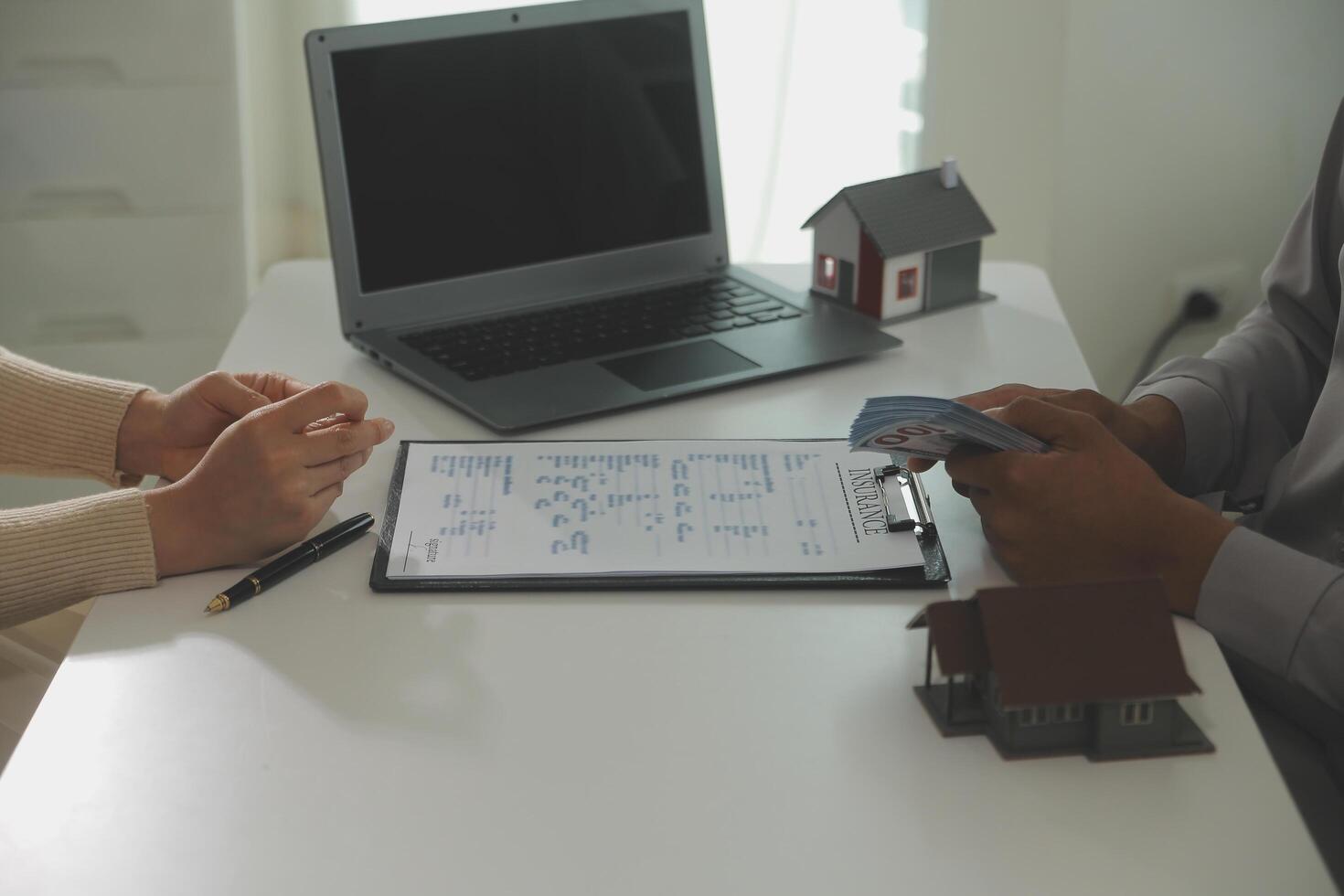 Real estate agent home sales broker is using a pen pointing to the house model and explains the business contract, rent, buy, mortgage, loan, or home insurance photo