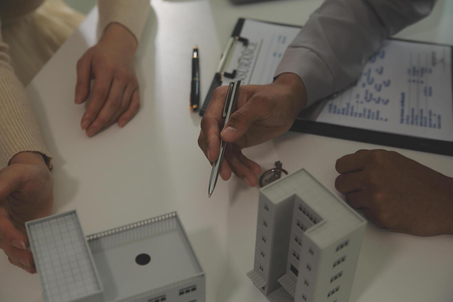 Real estate agent home sales broker is using a pen pointing to the house model and explains the business contract, rent, buy, mortgage, loan, or home insurance photo