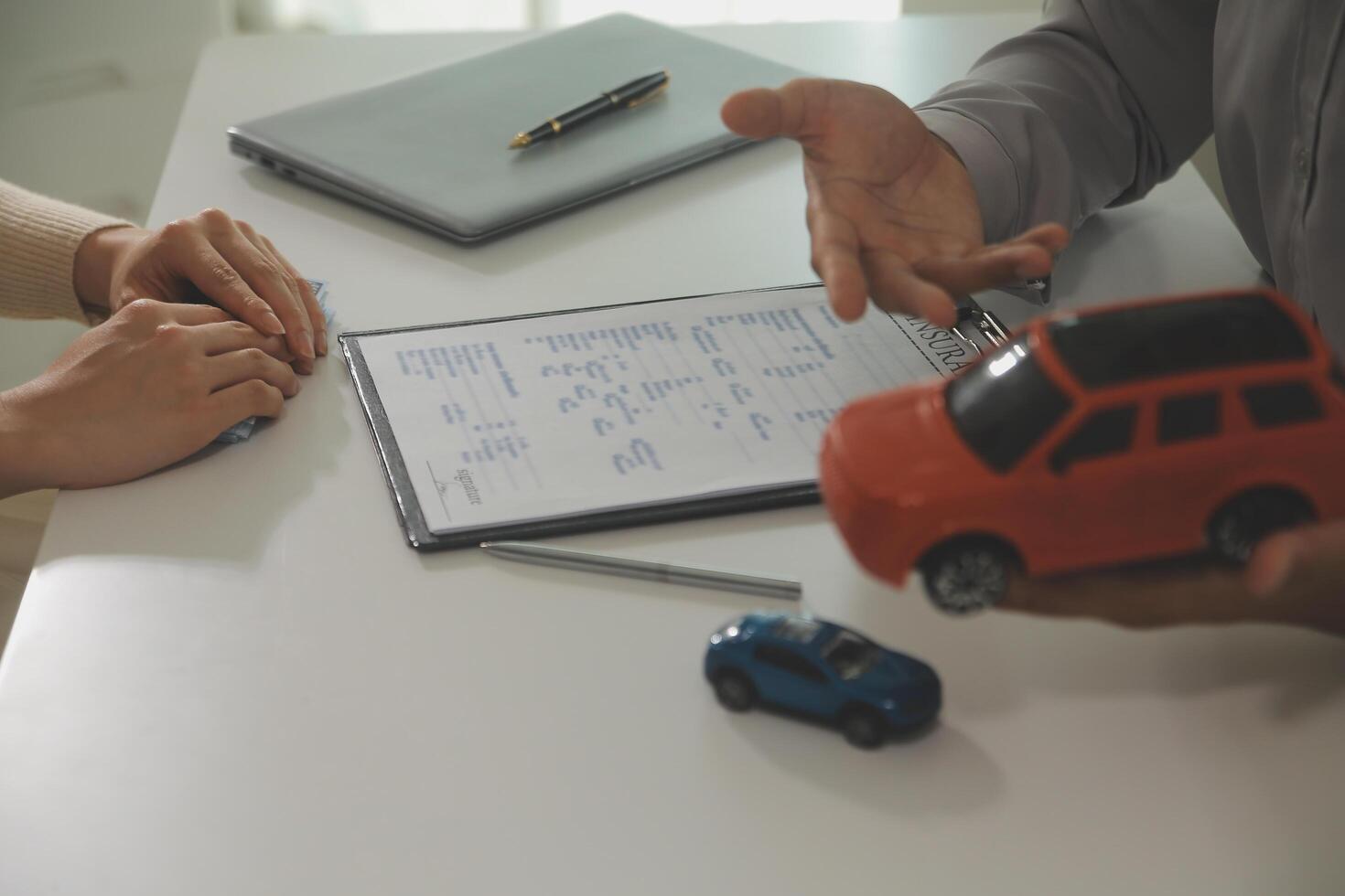 Young man receives a key from car salesman. After agreeing to a contract for rent or sale of a car at workshop, loan car, insurance, sale, buying car and finance concept. photo