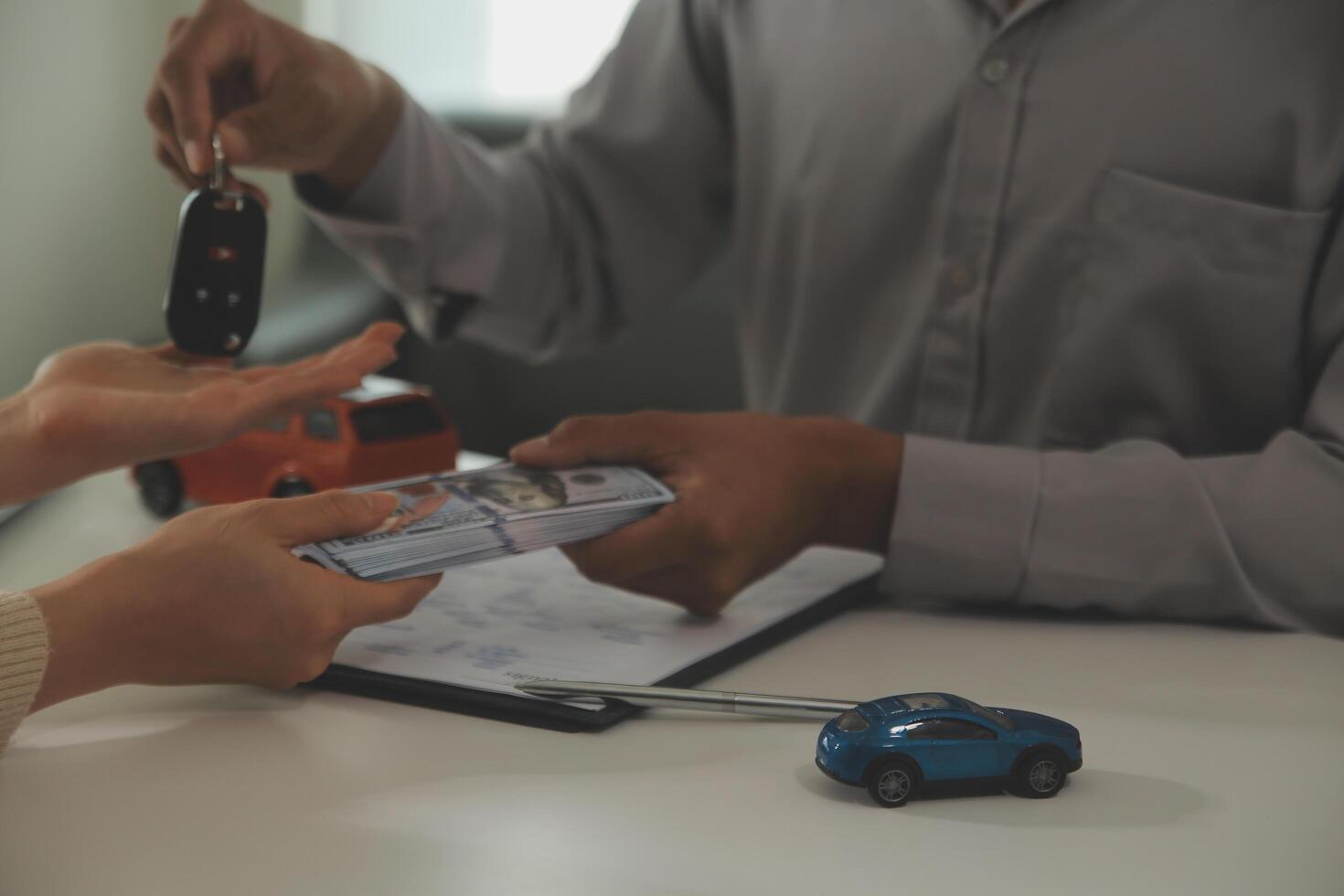 Young man receives a key from car salesman. After agreeing to a contract for rent or sale of a car at workshop, loan car, insurance, sale, buying car and finance concept. photo