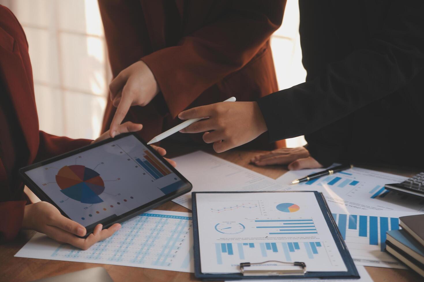 Group of confident business people point to graphs and charts to analyze market data, balance sheet, account, net profit to plan new sales strategies to increase production capacity. photo
