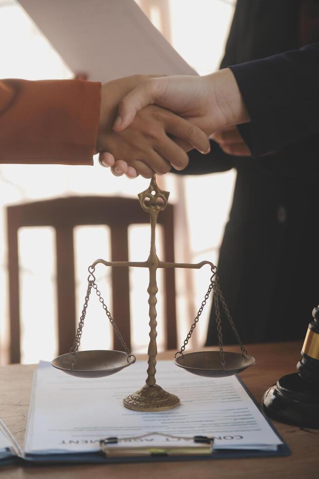 Lawyer shaking hands with a client making about documents, contracts, agreements, cooperation agreements with a female client at the lawyer's desk and a hammer at the table. photo