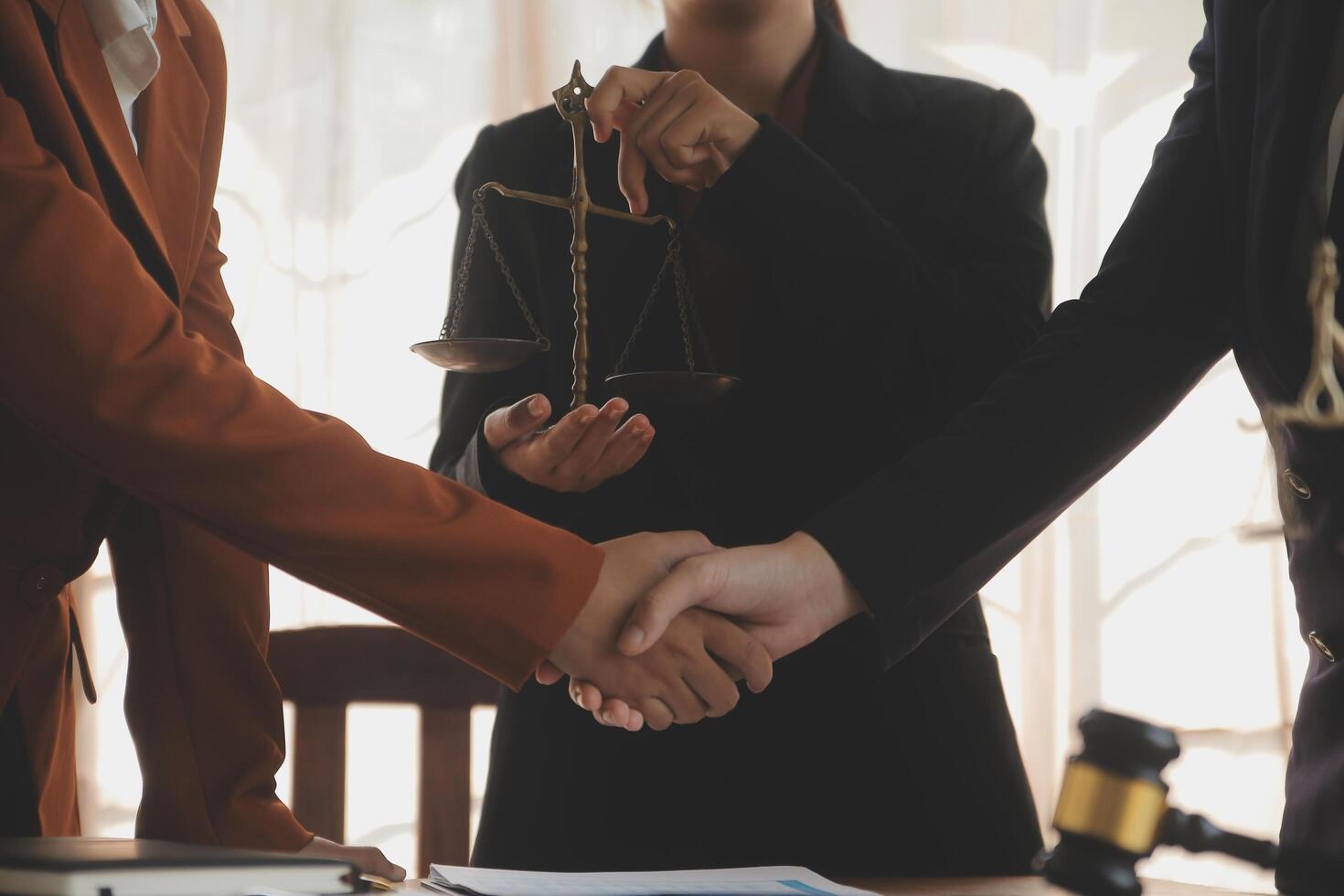 Lawyer shaking hands with a client making about documents, contracts, agreements, cooperation agreements with a female client at the lawyer's desk and a hammer at the table. photo