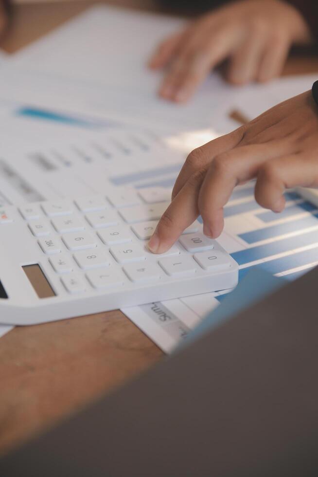 Group of confident business people point to graphs and charts to analyze market data, balance sheet, account, net profit to plan new sales strategies to increase production capacity. photo