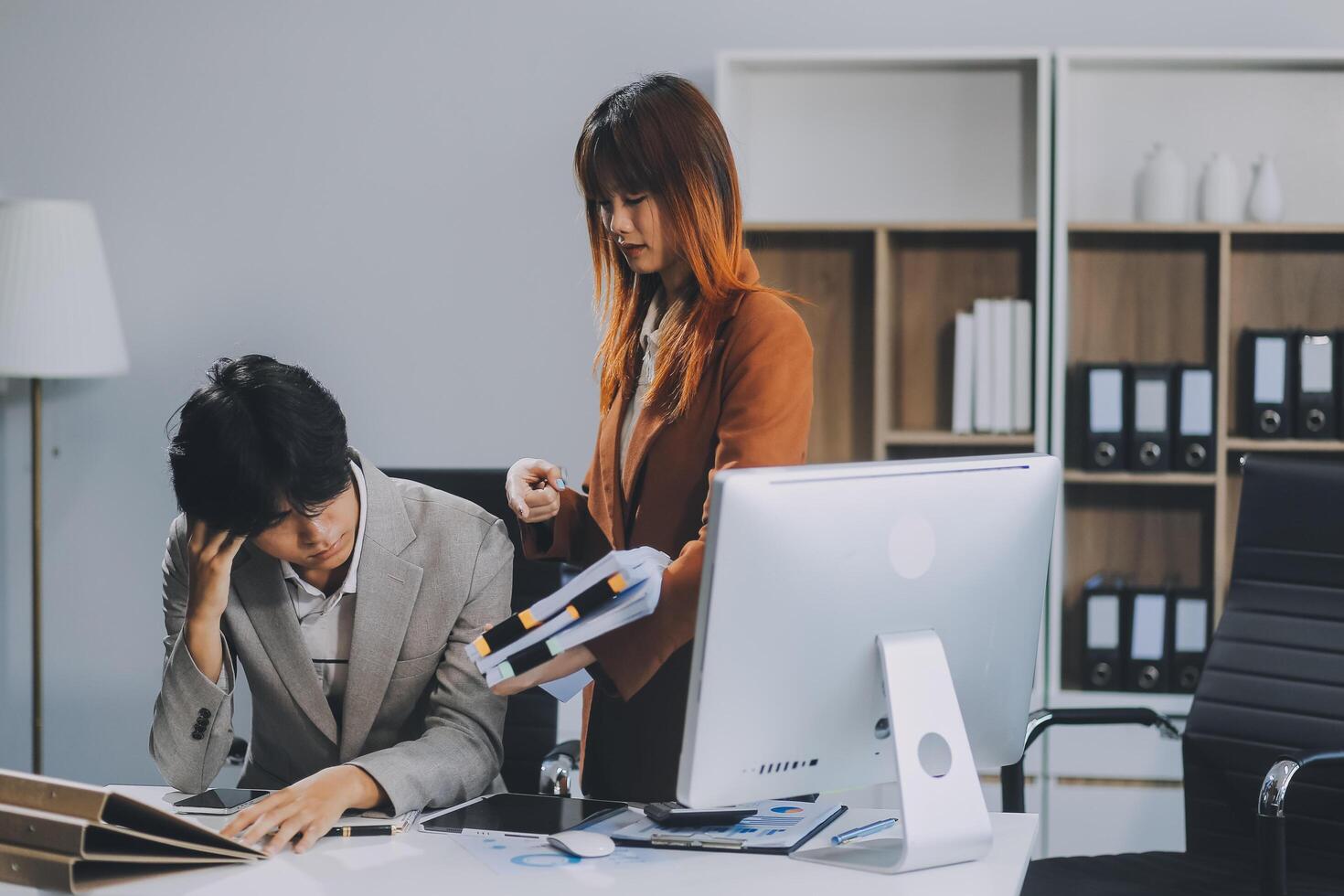Stressed business couple working at big cabinet. Frustrated director closed face with hands at laptop workplace interior. Woman partner solving problems on smartphone call feeling nervous at office photo