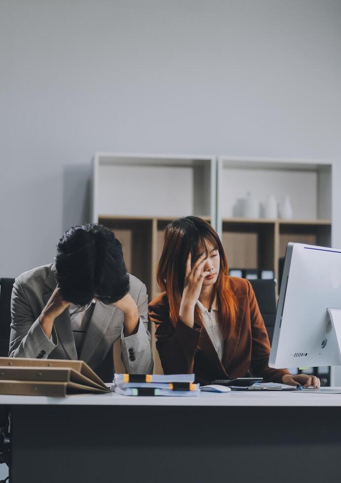 Stressed business couple working at big cabinet. Frustrated director closed face with hands at laptop workplace interior. Woman partner solving problems on smartphone call feeling nervous at office photo