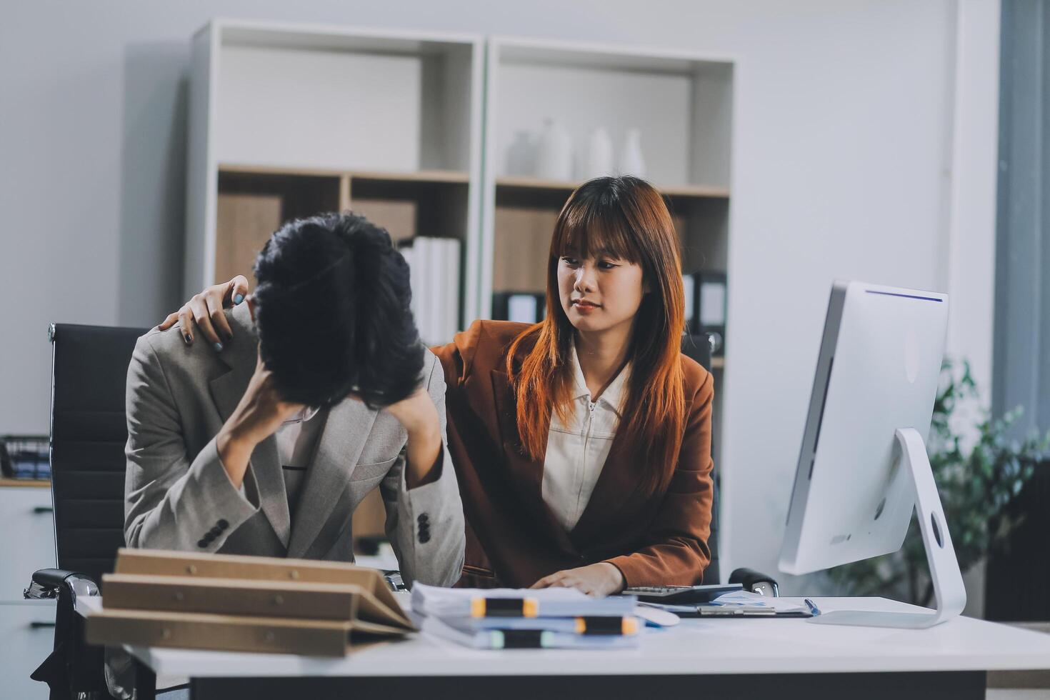 Stressed business couple working at big cabinet. Frustrated director closed face with hands at laptop workplace interior. Woman partner solving problems on smartphone call feeling nervous at office photo