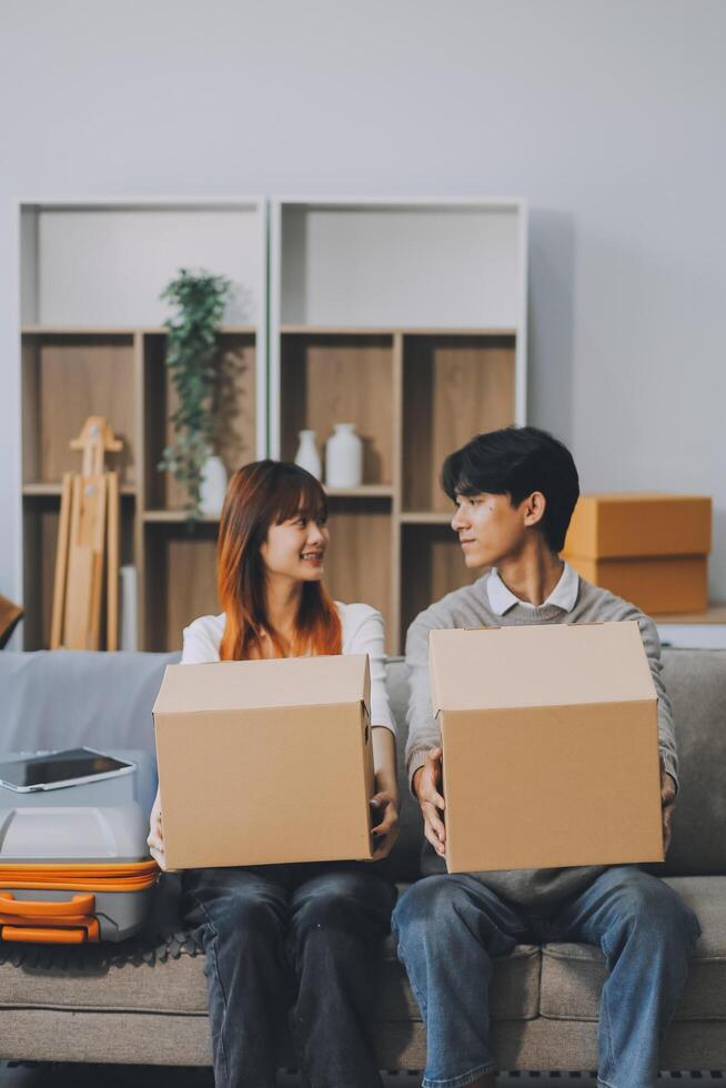 Young Asian couple relocating to a new house, joyfully packing and unpacking belongings. Expertise in moving, packing, togetherness, and creating a new home together. photo