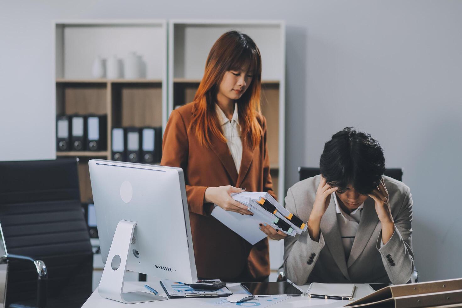 Stressed business couple working at big cabinet. Frustrated director closed face with hands at laptop workplace interior. Woman partner solving problems on smartphone call feeling nervous at office photo