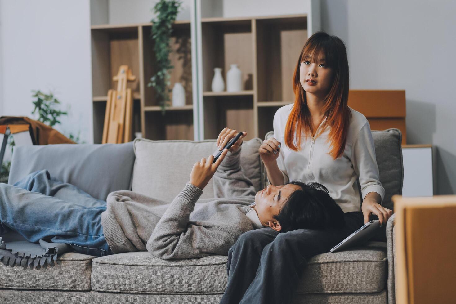 Young Asian couple relocating to a new house, joyfully packing and unpacking belongings. Expertise in moving, packing, togetherness, and creating a new home together. photo