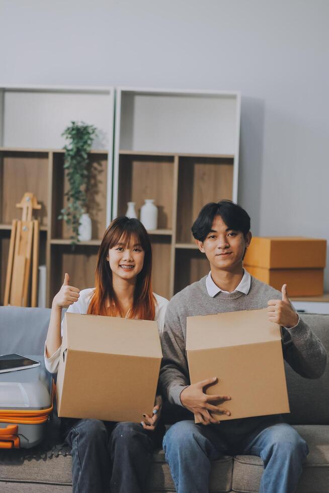 Young Asian couple relocating to a new house, joyfully packing and unpacking belongings. Expertise in moving, packing, togetherness, and creating a new home together. photo