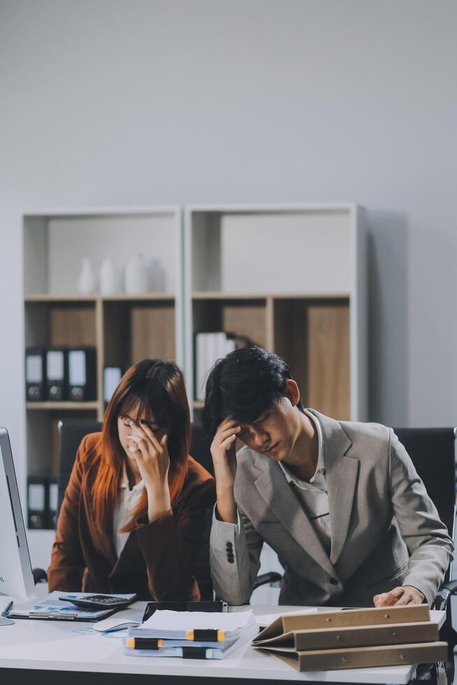 Stressed business couple working at big cabinet. Frustrated director closed face with hands at laptop workplace interior. Woman partner solving problems on smartphone call feeling nervous at office photo