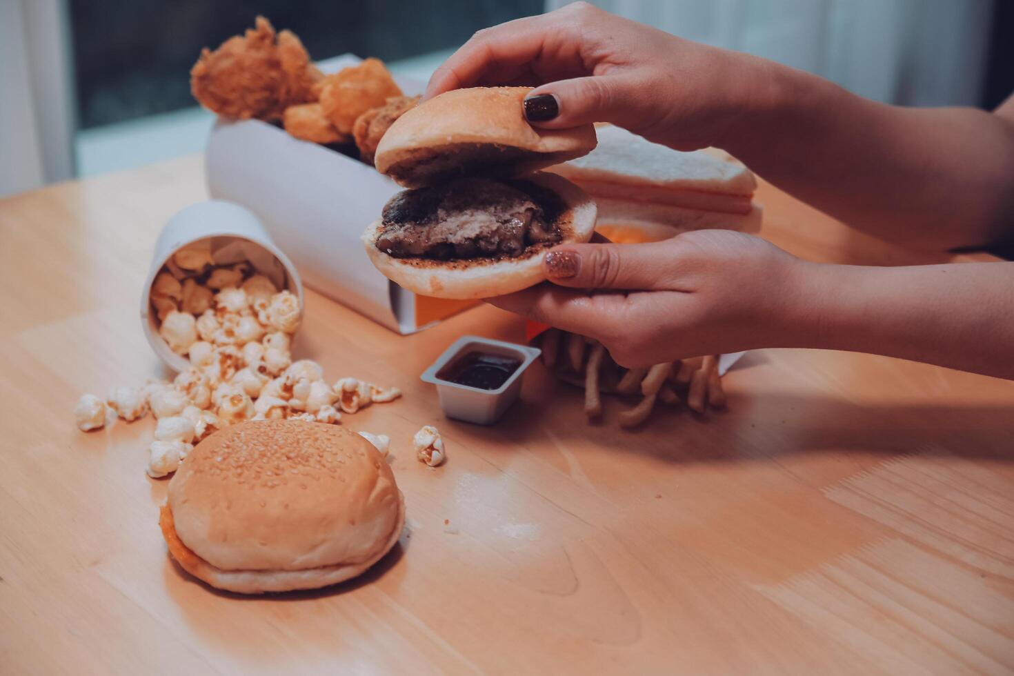 fast food, people and unhealthy eating concept - close up of woman hands holding hamburger or cheeseburger photo