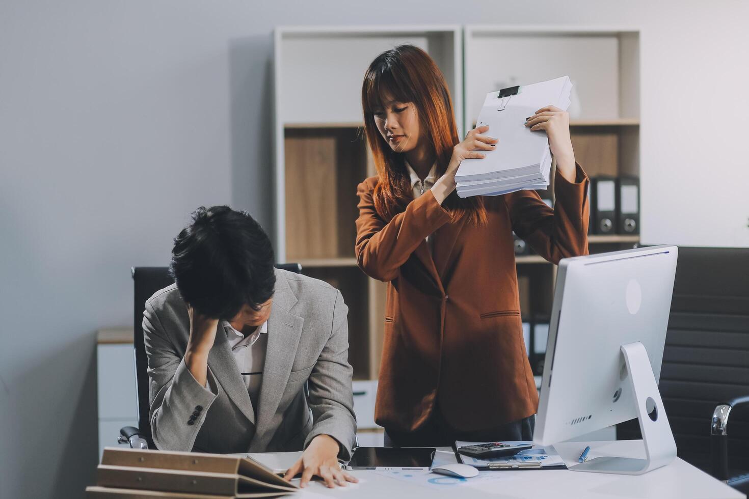 Stressed business couple working at big cabinet. Frustrated director closed face with hands at laptop workplace interior. Woman partner solving problems on smartphone call feeling nervous at office photo