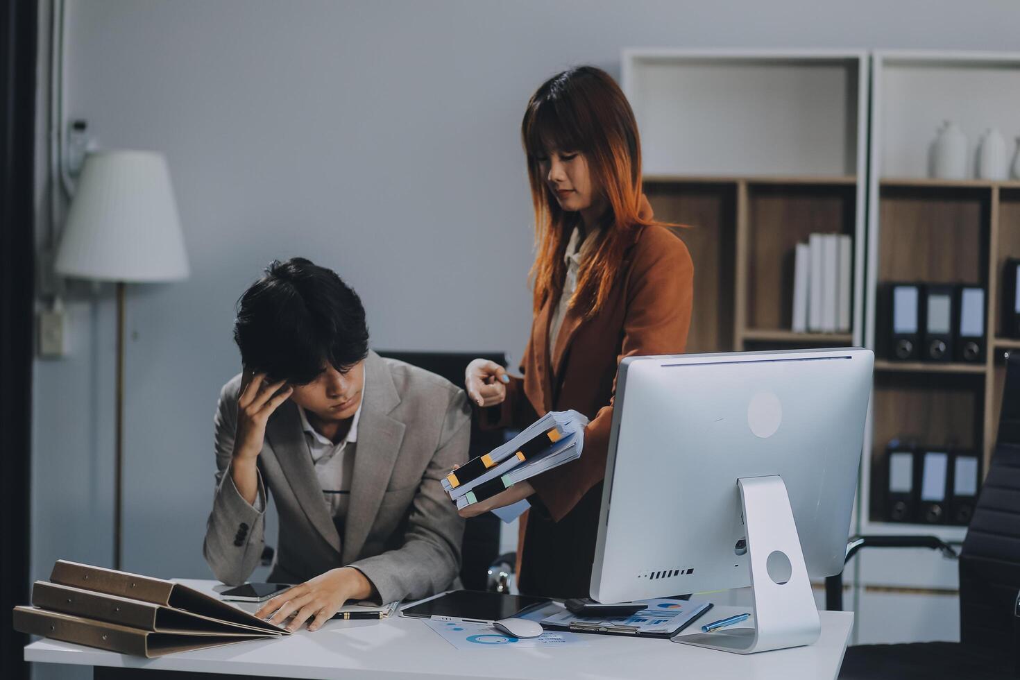 Stressed business couple working at big cabinet. Frustrated director closed face with hands at laptop workplace interior. Woman partner solving problems on smartphone call feeling nervous at office photo