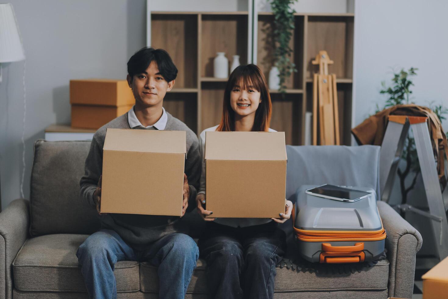 Young Asian couple relocating to a new house, joyfully packing and unpacking belongings. Expertise in moving, packing, togetherness, and creating a new home together. photo