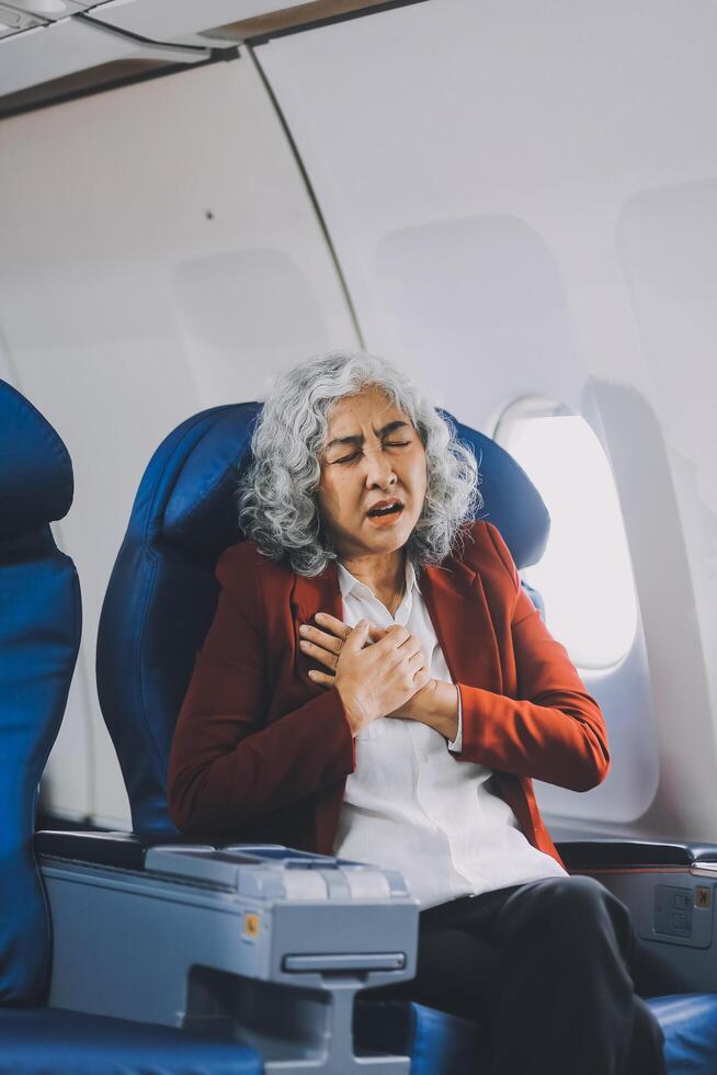 Mature with headache with nausea feeling sick while sitting in the airplane , Passengers near the window. photo