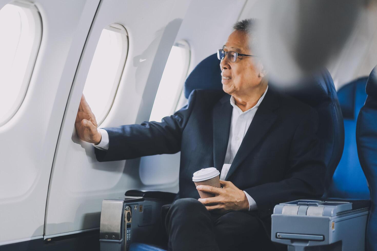 Attractive Asian male passenger of airplane sitting in comfortable seat while working laptop and tablet with mock up area using wireless connection. Travel in style, work with grace. photo