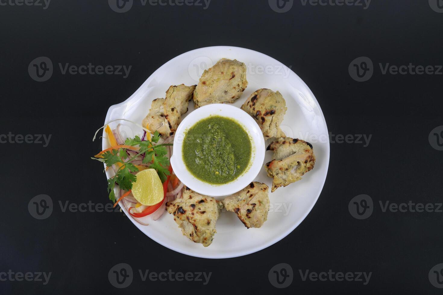 A plate with chicken on it and a bowl of sauce photo