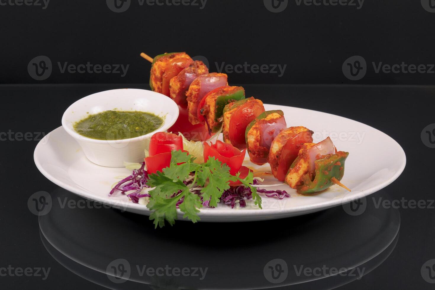 A plate with a skewered chicken and vegetables photo